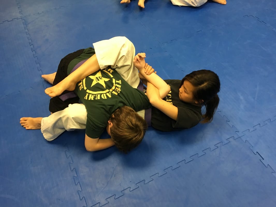 Kid working a jujitsu submission in class